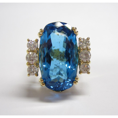 177 - A Blue Topaz and Diamond Cocktail Ring claw-set oval mixed-cut topaz, 31cts, between trios of brilli... 