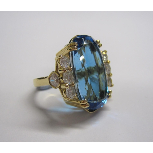 177 - A Blue Topaz and Diamond Cocktail Ring claw-set oval mixed-cut topaz, 31cts, between trios of brilli... 