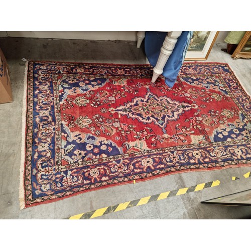 2 - A bordered Persian Rug on a red ground 8ft 2in x 4ft 5in A/F.