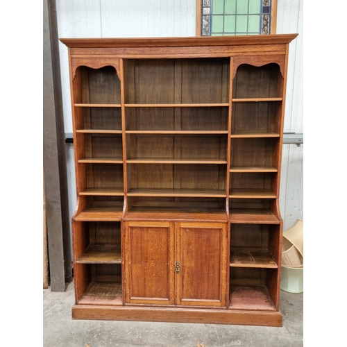 640 - An oak Bookcase of three bays of adjustable shelves above base fitted two bays of shelves flanking p... 