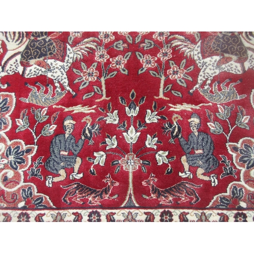 653 - A Turkish red ground Rug with design of figures on horseback and large central motif within multiple... 