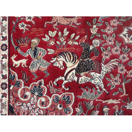 653 - A Turkish red ground Rug with design of figures on horseback and large central motif within multiple... 