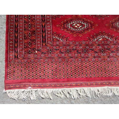 654 - A red ground Rug with multiple lozenges within border 6ft 6in x 4ft 2in