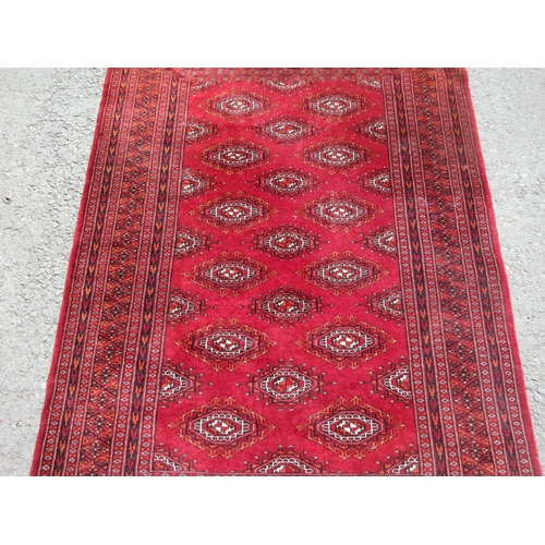 654 - A red ground Rug with multiple lozenges within border 6ft 6in x 4ft 2in