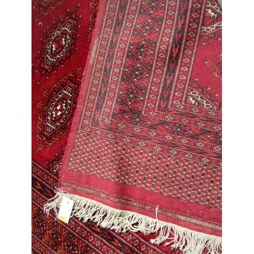 654 - A red ground Rug with multiple lozenges within border 6ft 6in x 4ft 2in