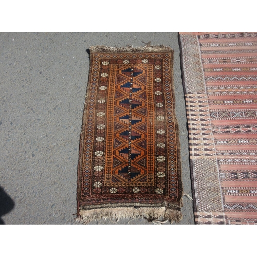 656 - A red ground Rug with striped design 6ft 4in x 3ft 6in, a Saddle Bag and a Wall Hanging