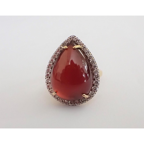 129 - A Garnet and Diamond Cocktail Ring claw-set pear-shaped garnet cabochon within frame of brilliant-cu... 