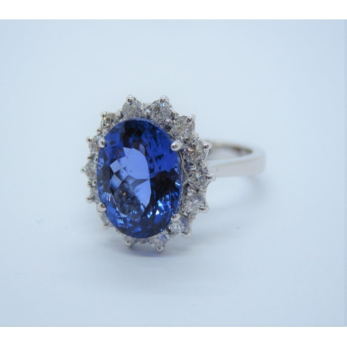 144 - A Tanzanite and Diamond Cluster Ring claw-set oval mixed-cut stone, 3.86cts, within a frame of brill... 