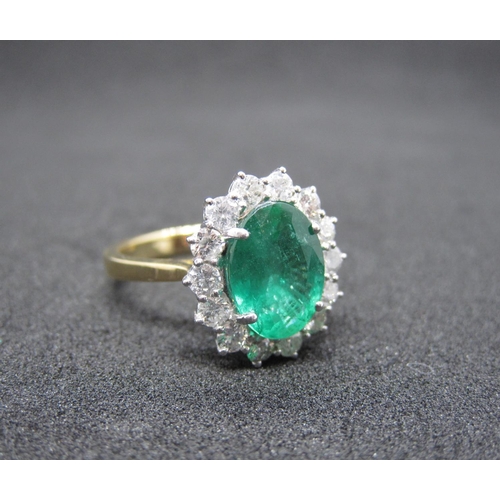 159 - An Emerald and Diamond Cluster Ring claw-set oval-cut emerald, 2.78cts, within a frame of fourteen b... 