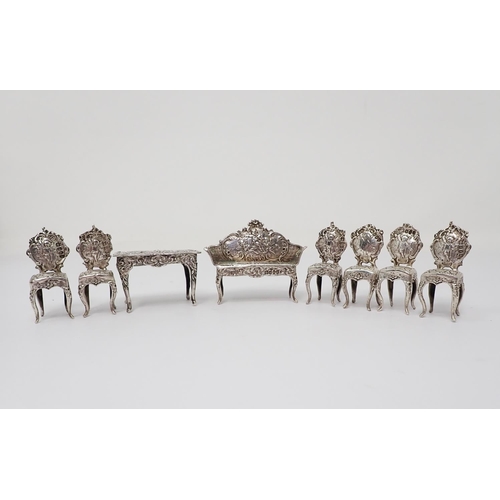 38 - A Victorian Continental silver miniature Table, Settee and six Chairs, decorated figures, scroll, et... 