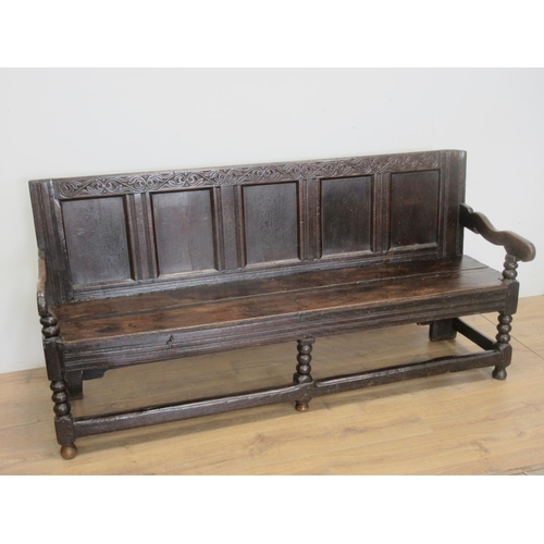 530 - A 17th Century oak Settle with scrolled leafage carved cresting rail above five panel back mounted u... 