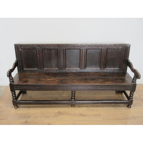 530 - A 17th Century oak Settle with scrolled leafage carved cresting rail above five panel back mounted u... 