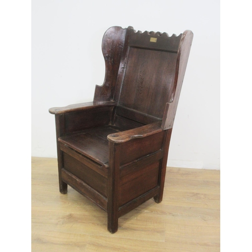 532 - An antique oak Lambing Chair with shaped top rail, inset brass plaque inscribed W.Smith 1850, wing b... 