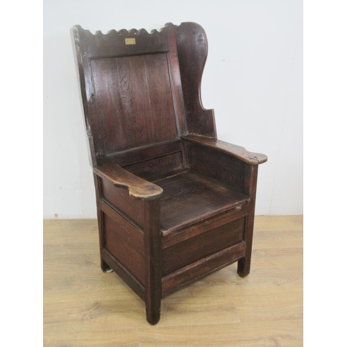 532 - An antique oak Lambing Chair with shaped top rail, inset brass plaque inscribed W.Smith 1850, wing b... 