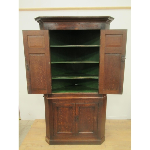 536 - An antique oak double Corner Cupboard with pair of panelled doors enclosing shaped shelves above ano... 