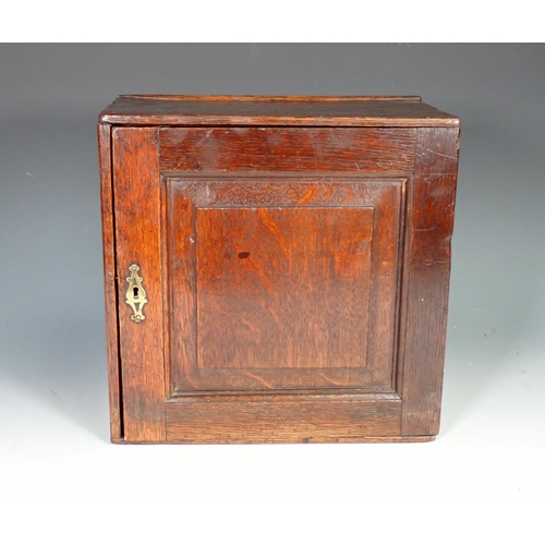 550 - An early 18th Century oak Spice Cupboard with fielded panelled door enclosing eight drawers, 11in sq... 