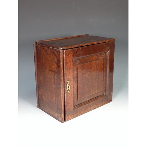 550 - An early 18th Century oak Spice Cupboard with fielded panelled door enclosing eight drawers, 11in sq... 