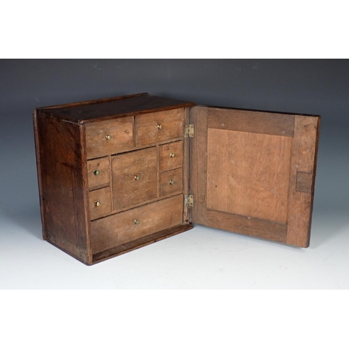 550 - An early 18th Century oak Spice Cupboard with fielded panelled door enclosing eight drawers, 11in sq... 