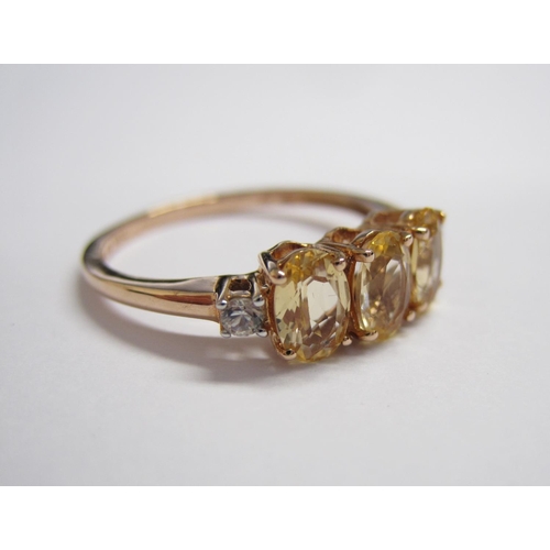 156 - An Imperial Topaz Ring claw-set three oval-cut stones, total weight 1.62cts, between two white zirco... 