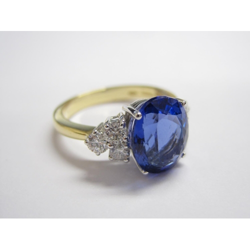 177 - A Tanzanite and Diamond Ring claw-set oval mixed-cut tanzanite, 4.10cts, between trios of brilliant-... 