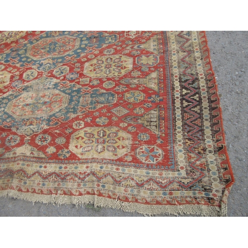 399 - A bordered Caucasian Carpet with four shaped oval blue ground medallions on a red ground with obelis... 