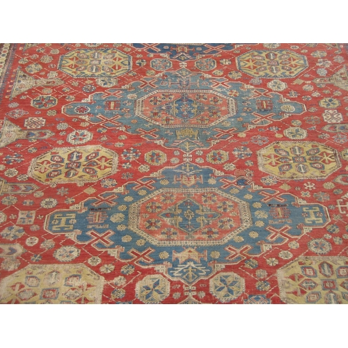 399 - A bordered Caucasian Carpet with four shaped oval blue ground medallions on a red ground with obelis... 