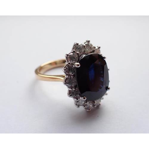 160 - A Sapphire and Diamond Cluster Ring claw-set oval-cut sapphire, 5.60cts, within frame of brilliant-c... 