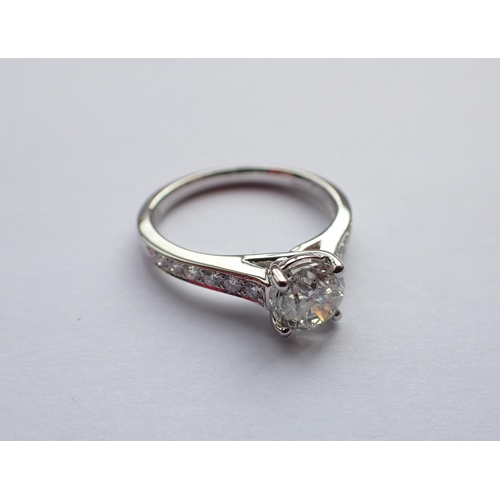 169 - A Diamond ring claw-set brilliant-cut stone, 1.00ct, between graduated pavé-set stones to shoulders ... 