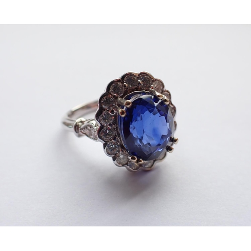 170 - A Sapphire and Diamond Cluster Ring claw-set oval-cut Ceylon sapphire, 3.04cts, within a frame of si... 