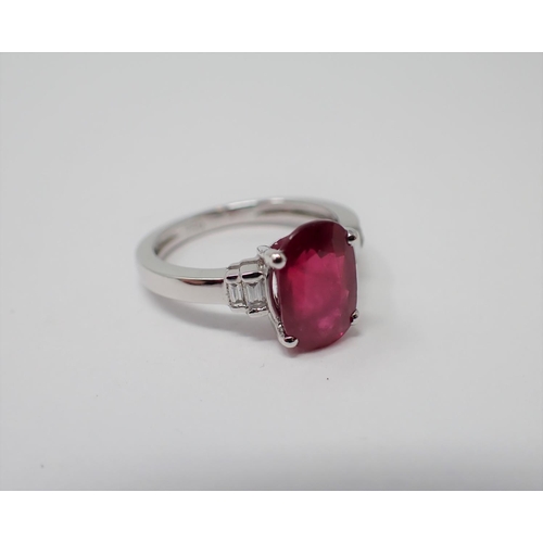 155 - A Ruby and Diamond Ring claw-set oval-cut ruby between two pairs of diamond baguettes in 18ct white ... 