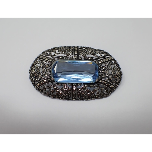 169 - An oval vintage Brooch set scissor-cut blue stone within openwork frame set marcasite, stamped 925