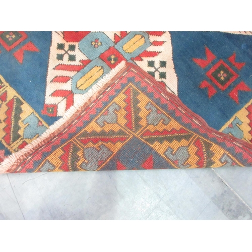 375 - A Persian Rug with geometric designs to the border and three central lozenges on a blue ground, 6ft ... 