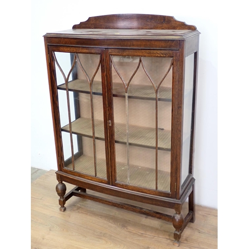 99 - An oak and glazed bow fronted two door Display Cabinet on bulbous turned supports 4ft 7in H x 2ft 11... 