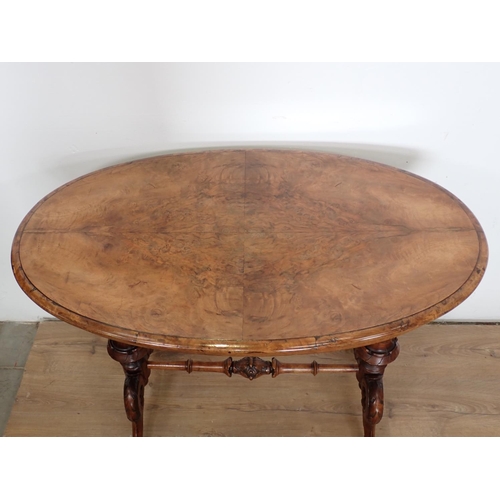 1029 - A Victorian walnut oval Centre Table on cheval frame with turned supports and stretchers, scroll fee... 