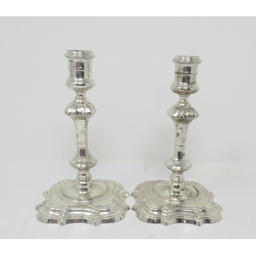 865 - A pair of George II silver cast Candlesticks with reel shaped sconces, knopped stems on shaped squar... 