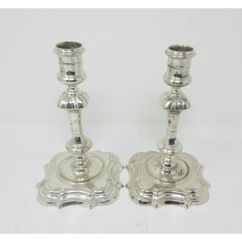 865 - A pair of George II silver cast Candlesticks with reel shaped sconces, knopped stems on shaped squar... 