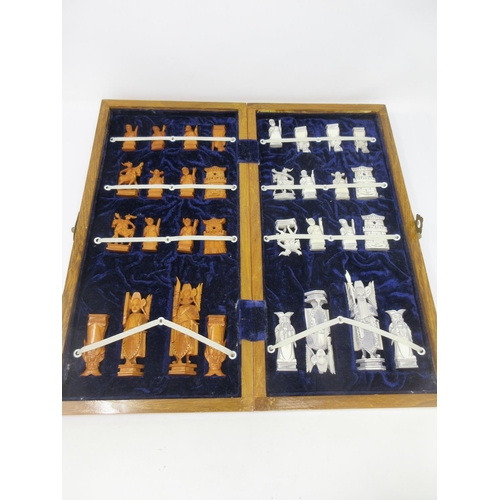 964 - A carved Chinese style Chess Set in a folding case having chessboard top 16 x 8in