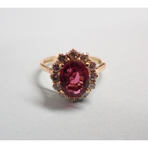 169 - A Pink Tourmaline and Diamond cluster Ring claw-set oval-cut tourmaline within a frame of twelve bri... 