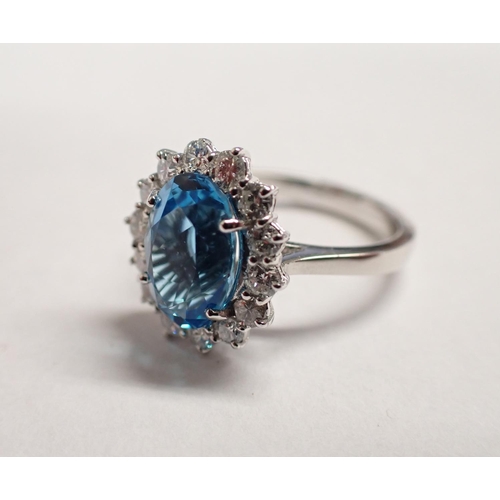 184 - A Blue Topaz and Diamond Cluster Ring claw-set oval-cut topaz, 3.48cts, within frame of brilliant-cu... 