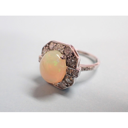 185 - An Art Deco style Opal and Diamond Ring claw-set oval opal cabochon within a frame of brilliant and ... 