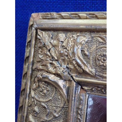 597 - A gilt framed Wall Mirror with designs of scrolls and foliate detail, 2ft 6in x 1ft 11in