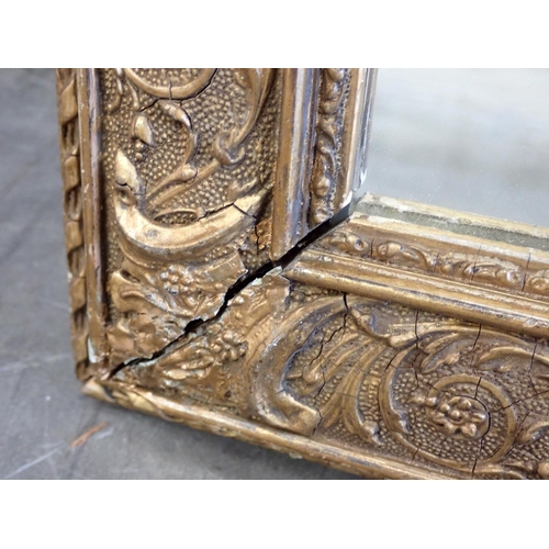 597 - A gilt framed Wall Mirror with designs of scrolls and foliate detail, 2ft 6in x 1ft 11in