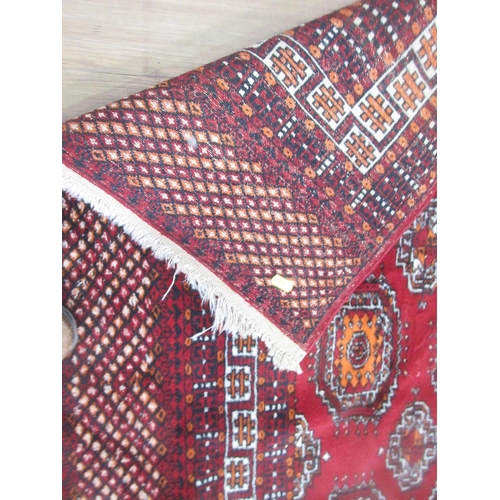 6 - A bordered Bokhara type red ground Rug with all over guls to the field, 5ft 10in x 4ft