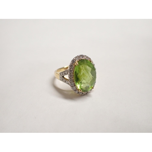 168 - A Peridot and Diamond Cluster Ring claw-set faceted oval peridot within frame of pavé-set brilliant-... 