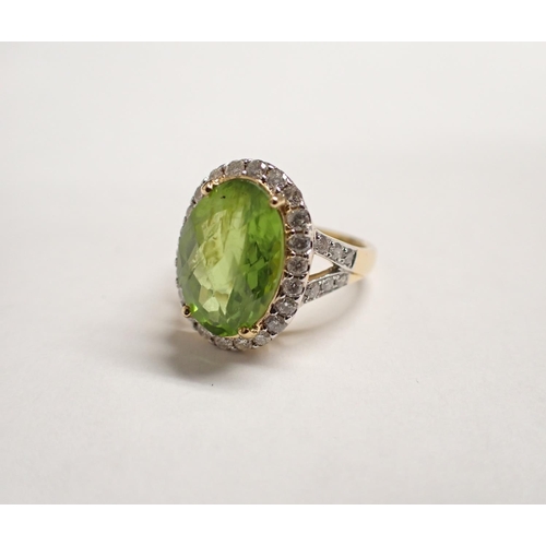 168 - A Peridot and Diamond Cluster Ring claw-set faceted oval peridot within frame of pavé-set brilliant-... 