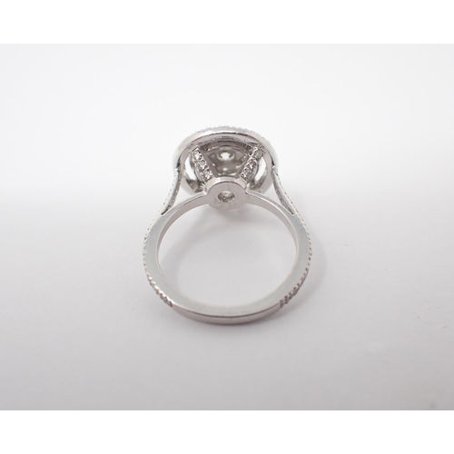 172 - A Diamond Halo Cluster Ring the principle brilliant-cut stone set within eight smaller stones and tw... 