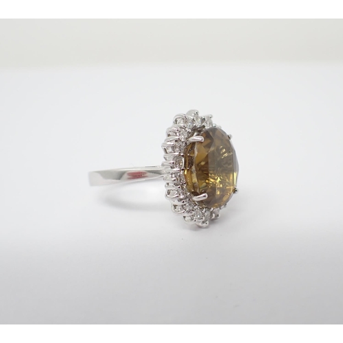 179 - A Zircon and Diamond Cluster Ring claw-set oval mixed-cut yellow/brown zircon, 6cts, within a frame ... 