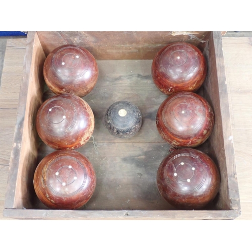 357 - A pine box containing six turned lignum Bowling Bowls and a Jack