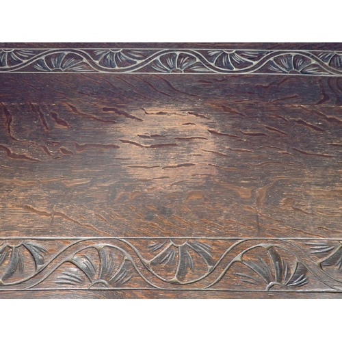 501 - An early 20th Century oak Monk's Bench with mask and leafage carved front panel 2ft 11in W x 2ft 5in... 