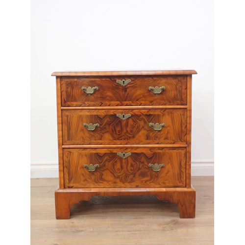 580 - A reproduction walnut Chest of small proportions with quartered moulded top fitted three drawers on ... 